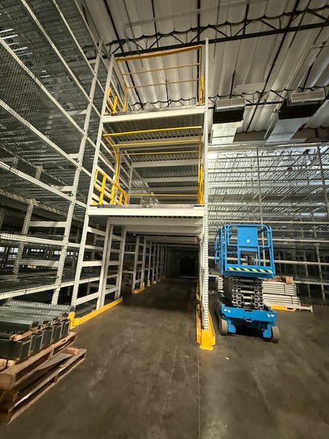 Rack-supported multi-tier archive structure under construction with a scissor lift on the floor